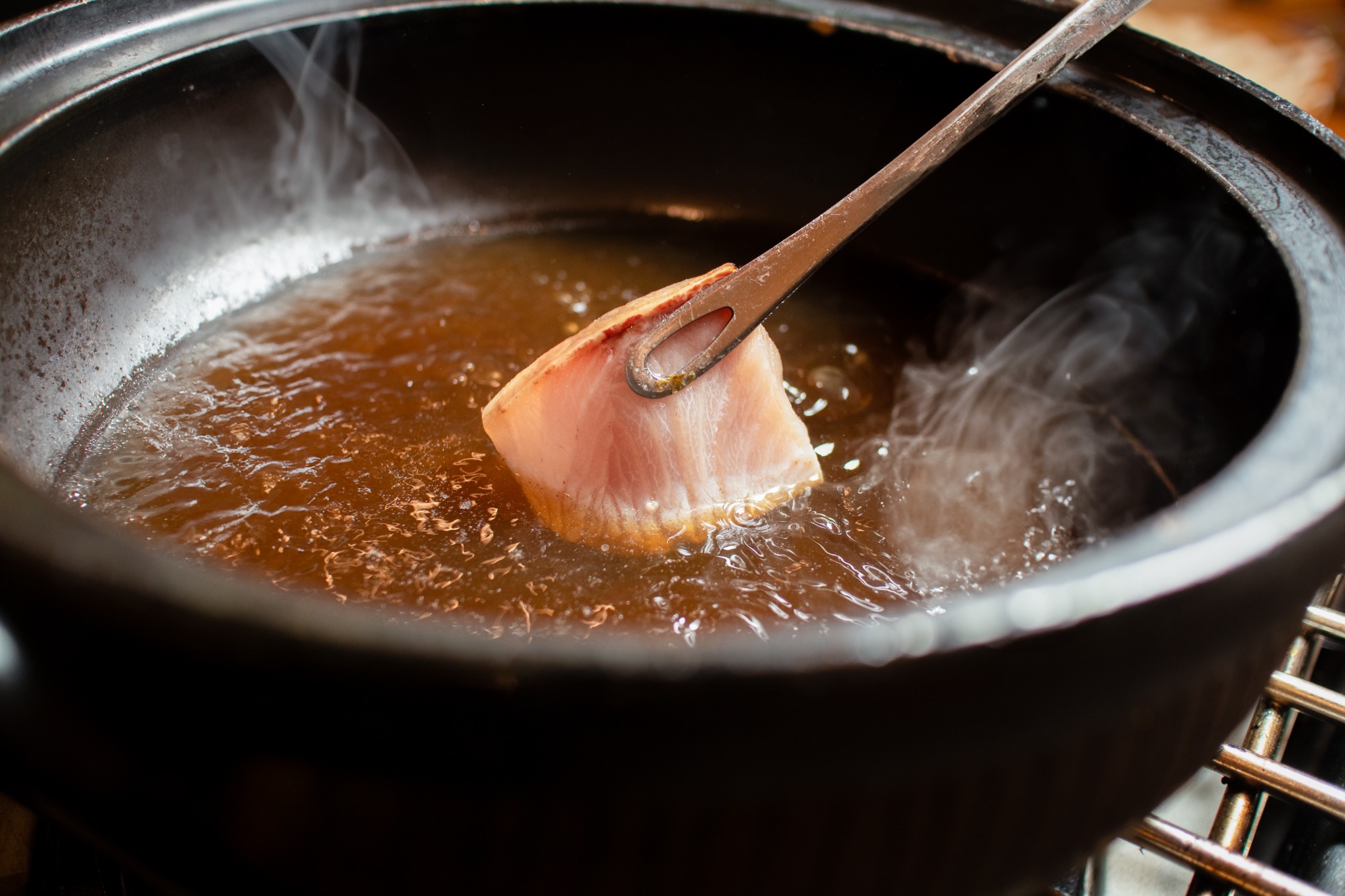 A seasonal fish course being prepared in warm broth at Tsubame